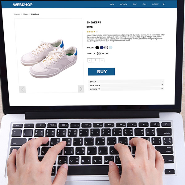 Hands typing on a laptop ordering shoes online